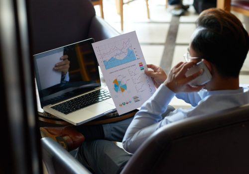 freecompress-vista-sobre-el-hombro-del-hombre-multitarea-revisando-documentos-financieros-y-teniendo-chat-telefonico